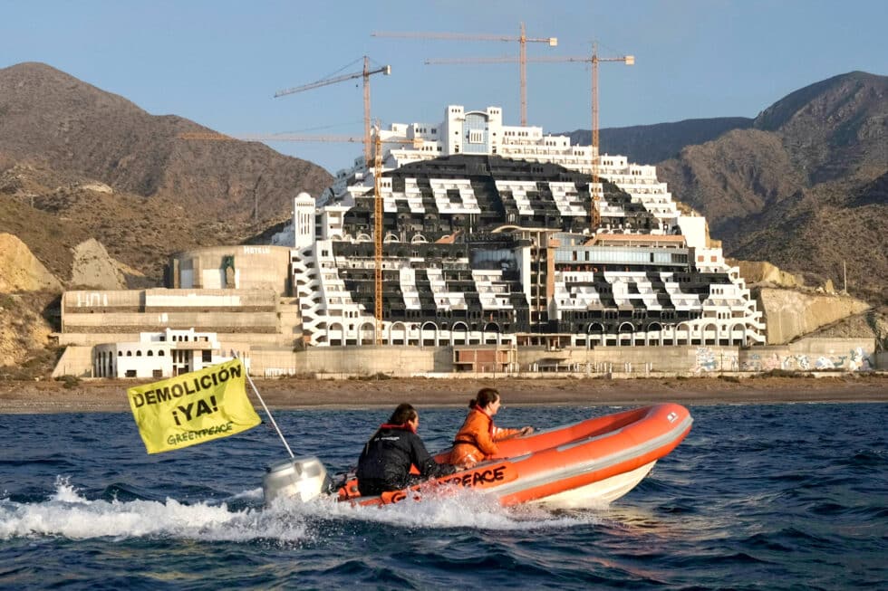 una zodiac pasa junto delante del hotel El Algarrobico que luce un punto negro gigante en su fachada