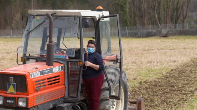 Una mujer, Lola Martínez ara con marcarilla en su tractor para plantar patatas en su finca de Chamoso, O Corgo, en Lugo, Galicia (España).