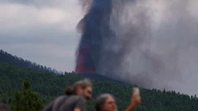 Varias personas observan la actividad de la erupción volcánica.