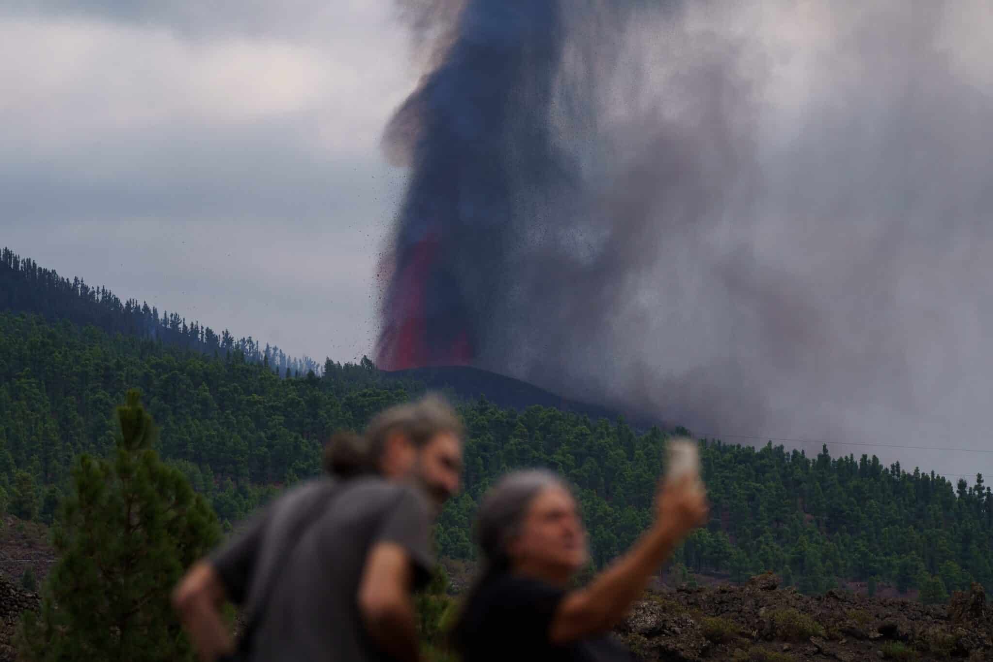 Varias personas observan la actividad de la erupción volcánica.