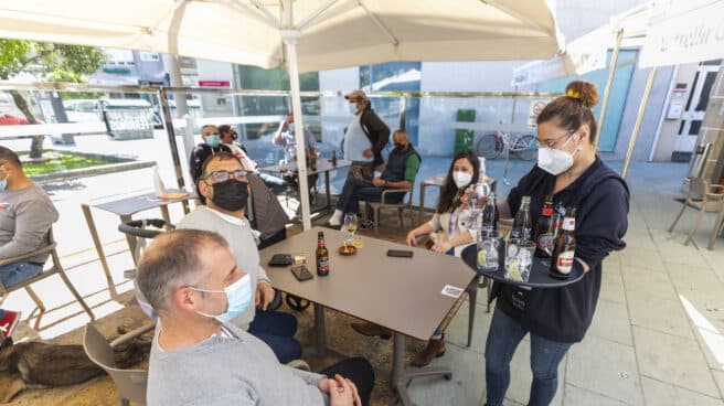 Una camarera sirve refrescos en una una mesa situada en la terraza de un restaurante