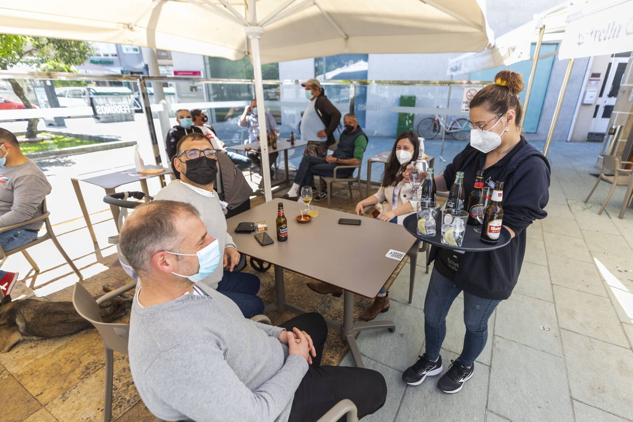 Una camarera sirve refrescos en una una mesa situada en la terraza de un restaurante