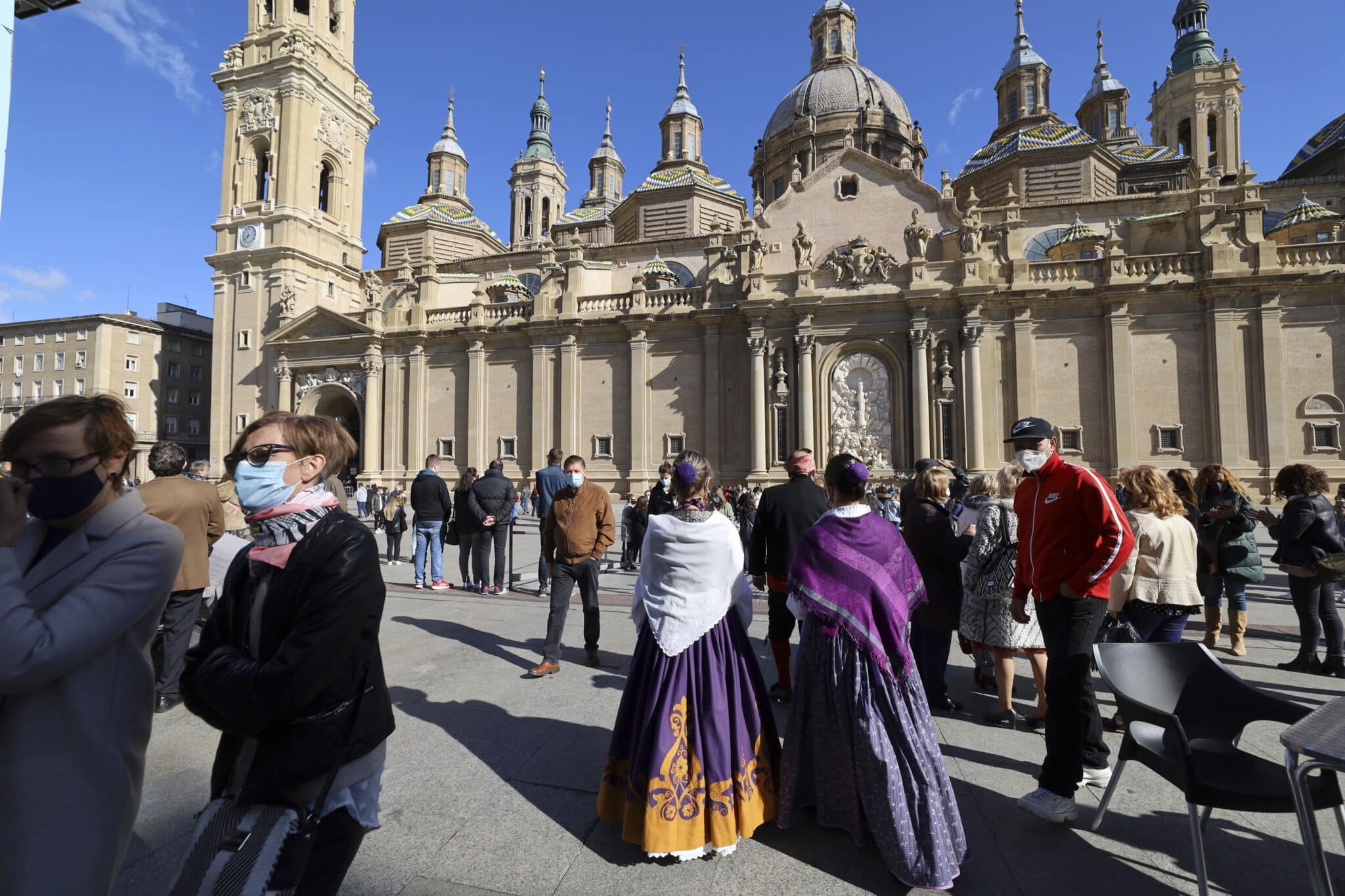 Varias personas vestidas de maños se concentran en las inmediaciones de la Basílica del Pilar