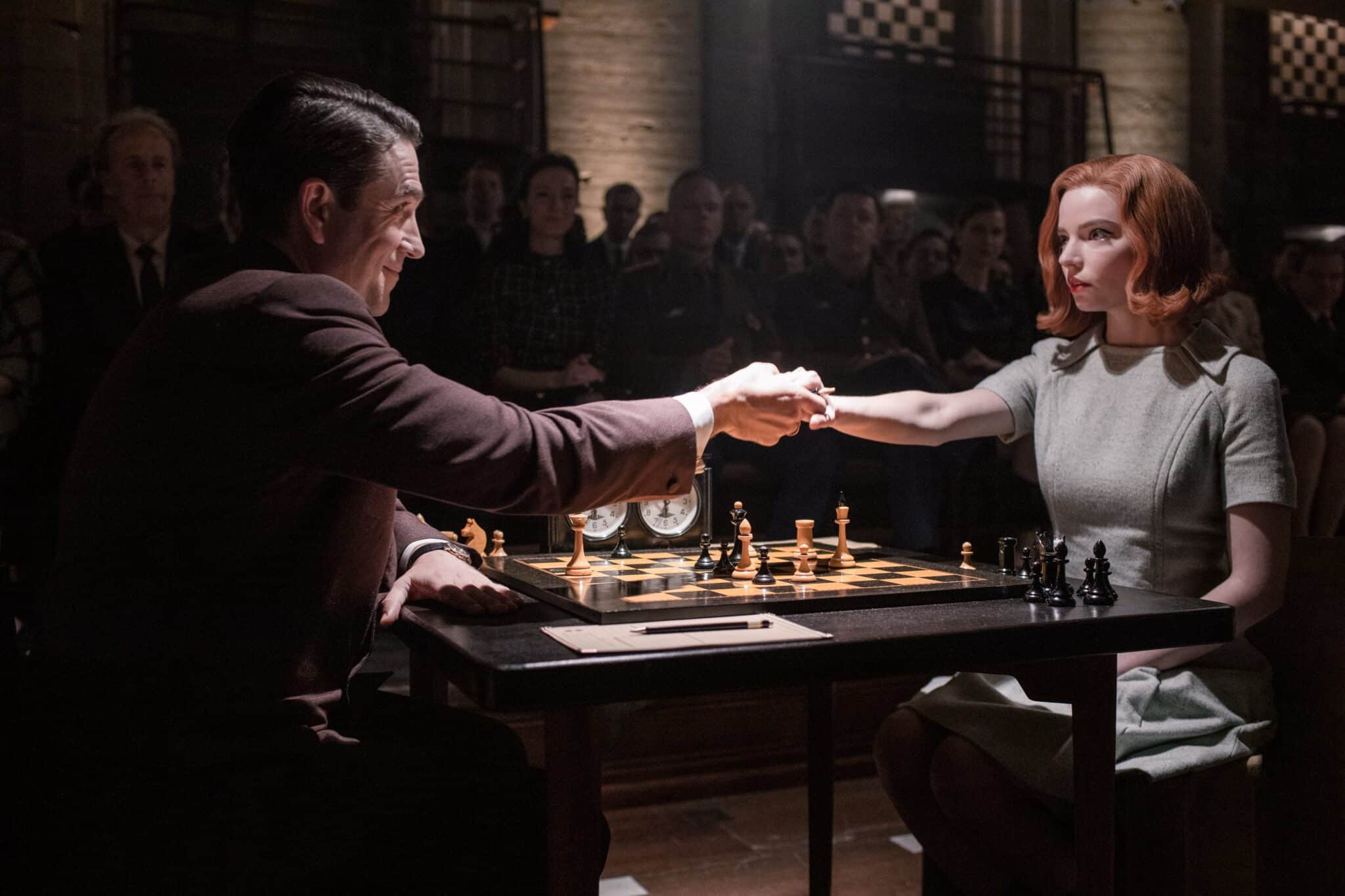 Actores de la serie de Gambito de Dama dandose la mano en una mesa de ajedrez