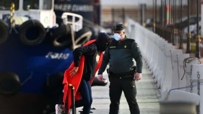 Un agente de la Guardia Civil ayuda a desembarcar a migrantes en Ceuta.