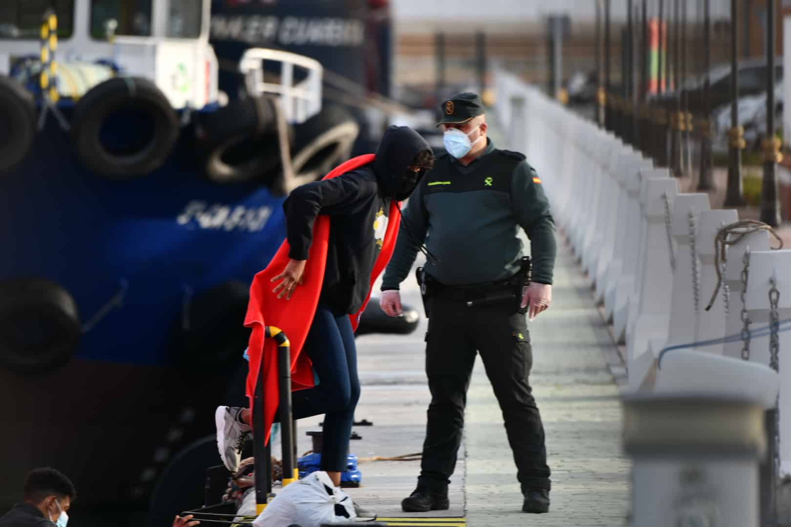 Un agente de la Guardia Civil ayuda a desembarcar a migrantes en Ceuta.