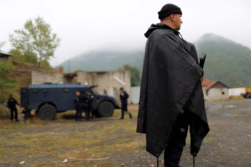 Un policía kosovar, con chubasquero y arma automática.