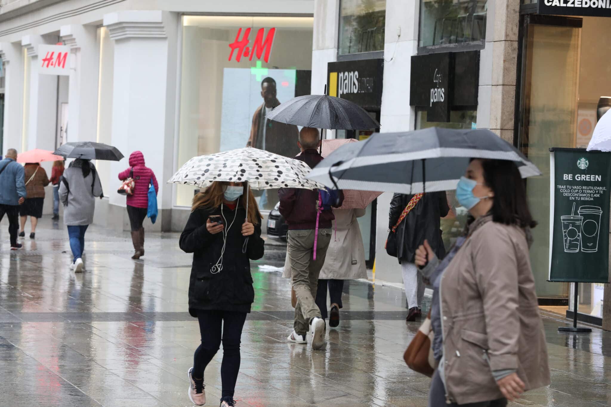 Transeúntes caminan por el centro de la capital protegiéndose de la lluvia con paraguas