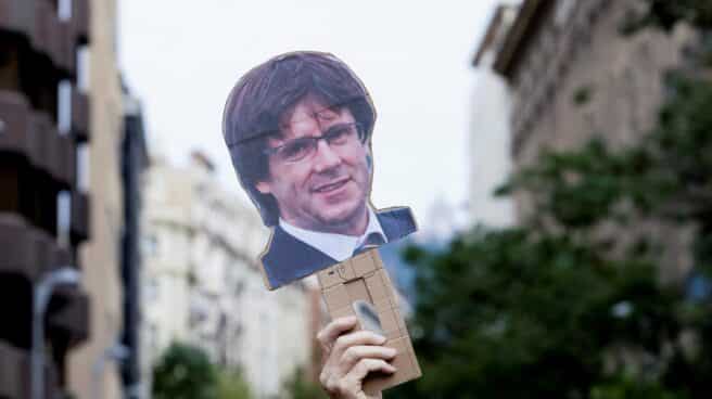 Una mano levanta una careta de Carles Puigdemont durante una manifestación en Barcelona.