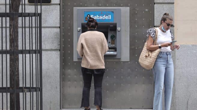 Dos mujeres frente a un cajero de Banco Sabadell.