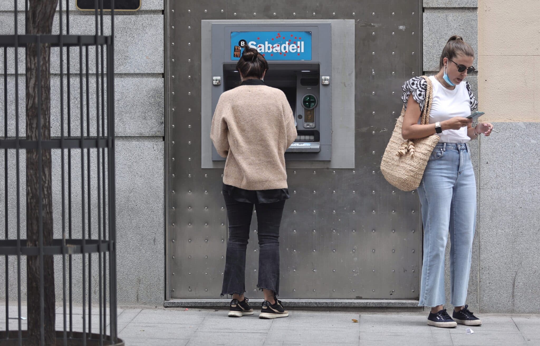 Dos mujeres frente a un cajero de Banco Sabadell.