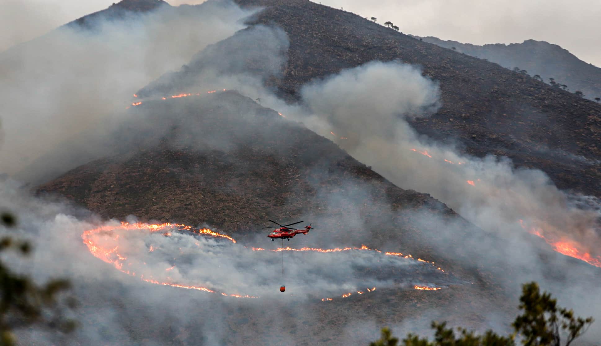 Helicóptero contra incendio intentando apagar el fuego de la Sierra Bermeja, visto desde el cerro de la Silla de los Huesos