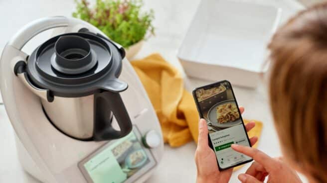 Imagen de una mujer con su teléfono móvil y una Thermomix. Imagen de una mujer con su teléfono móvil y una Thermomix.