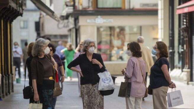 Varias personas con mascarillas conversan en una calle del centro de Sevilla.