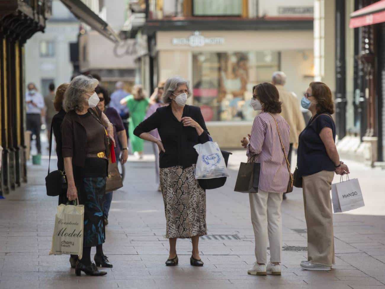 Varias personas con mascarillas conversan en una calle del centro de Sevilla.