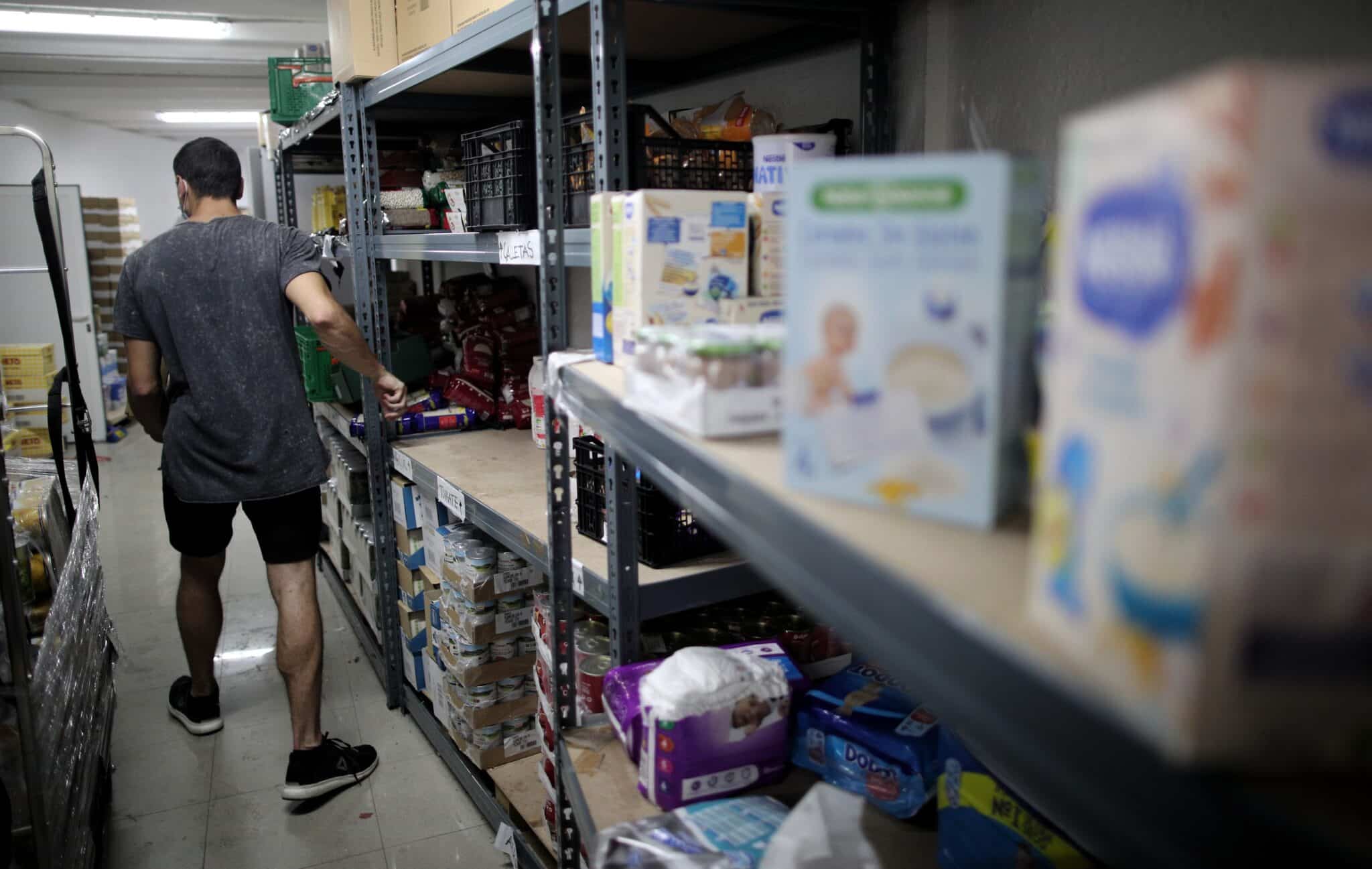 Un voluntario prepara productos antes de entregarlos a las puertas de la Parroquia Santa María Micaela de Madrid.