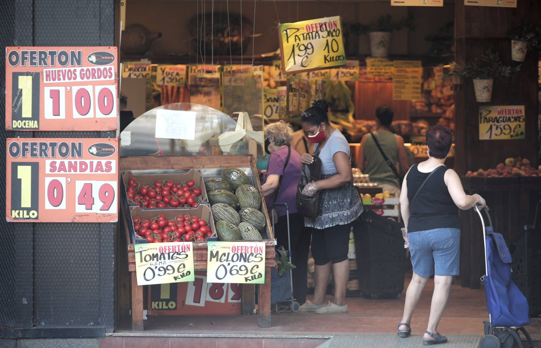 Varias personas compran en una frutería.