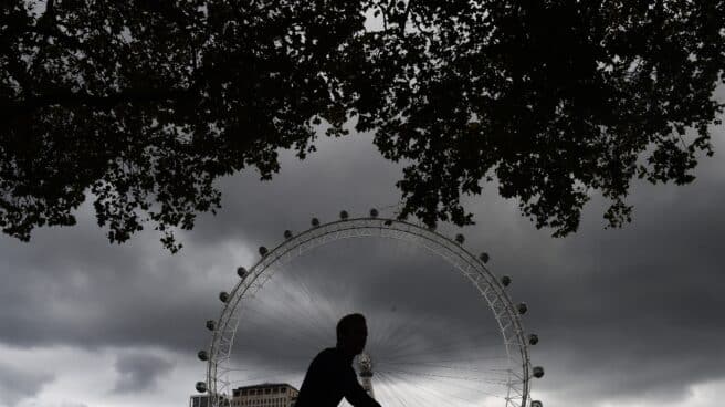 Un hombre en bicicleta pasa al lado de la noria de Londres.