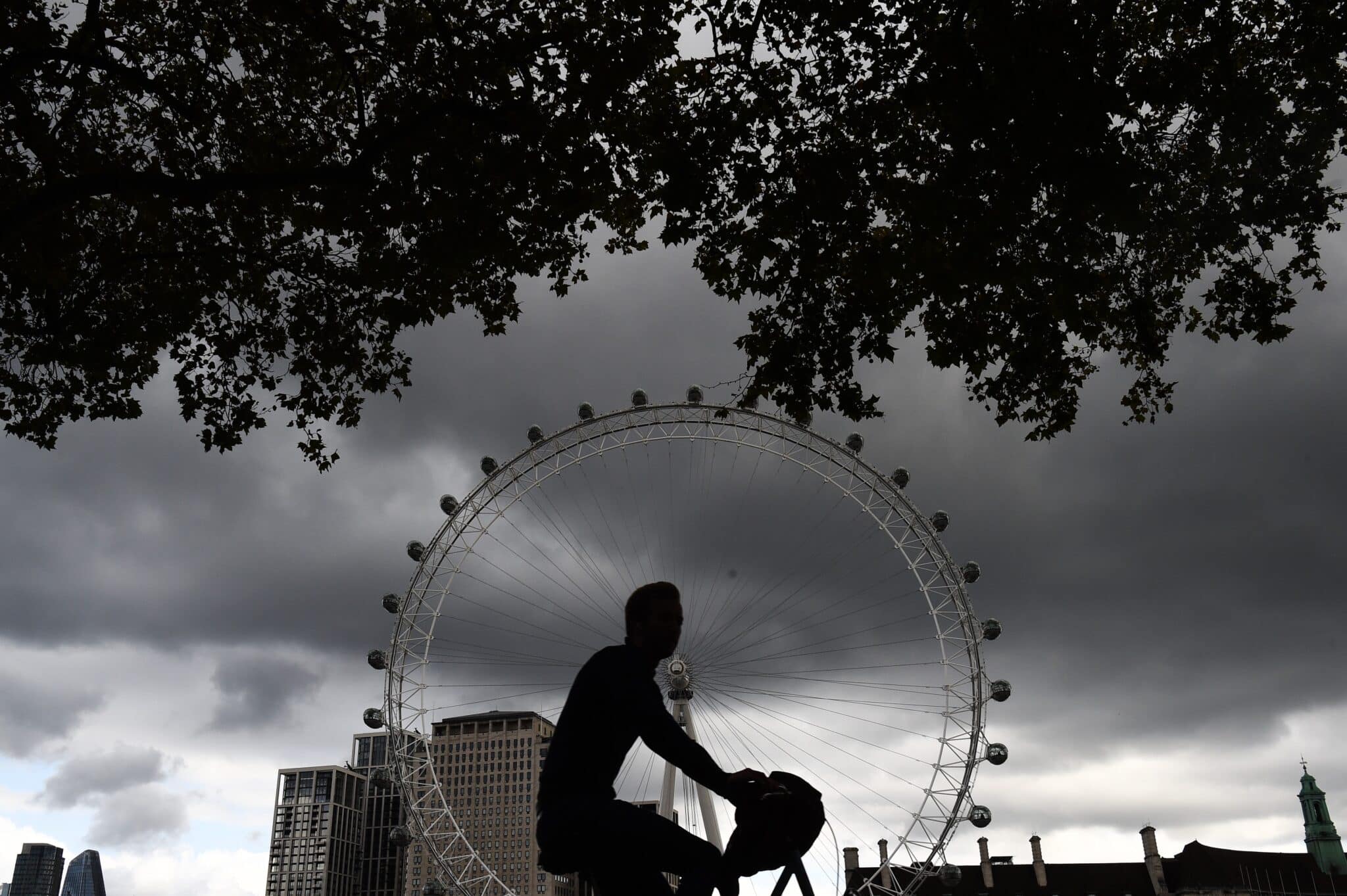 Un hombre en bicicleta pasa al lado de la noria de Londres.