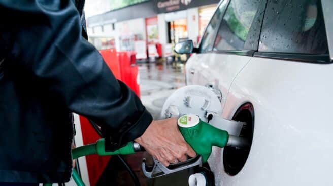 Mujer pone gasolina en un vehículo blanco de una gasolinera en Madrid