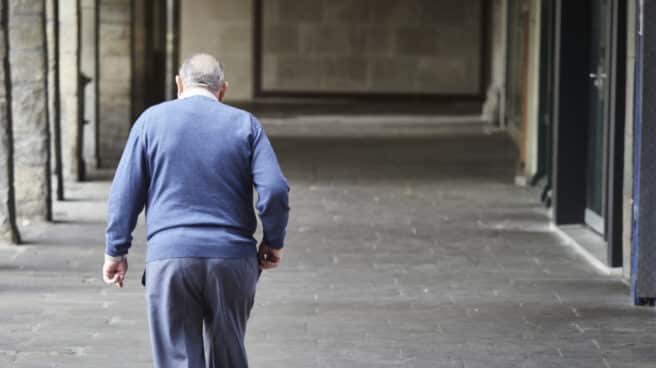 Un hombre mayor camina por una galería en el centro de Pamplona.