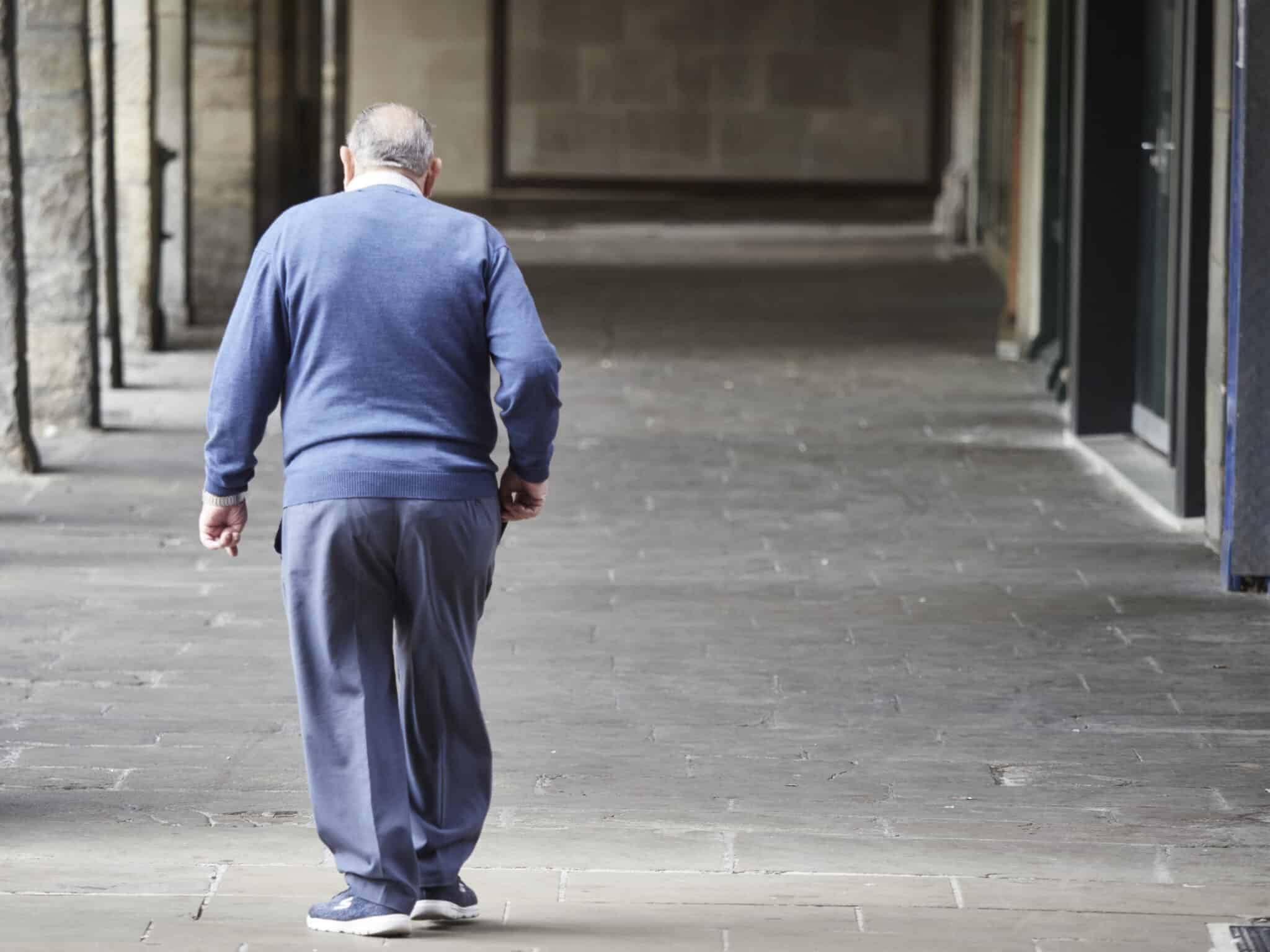 Un hombre mayor camina por una galería en el centro de Pamplona.