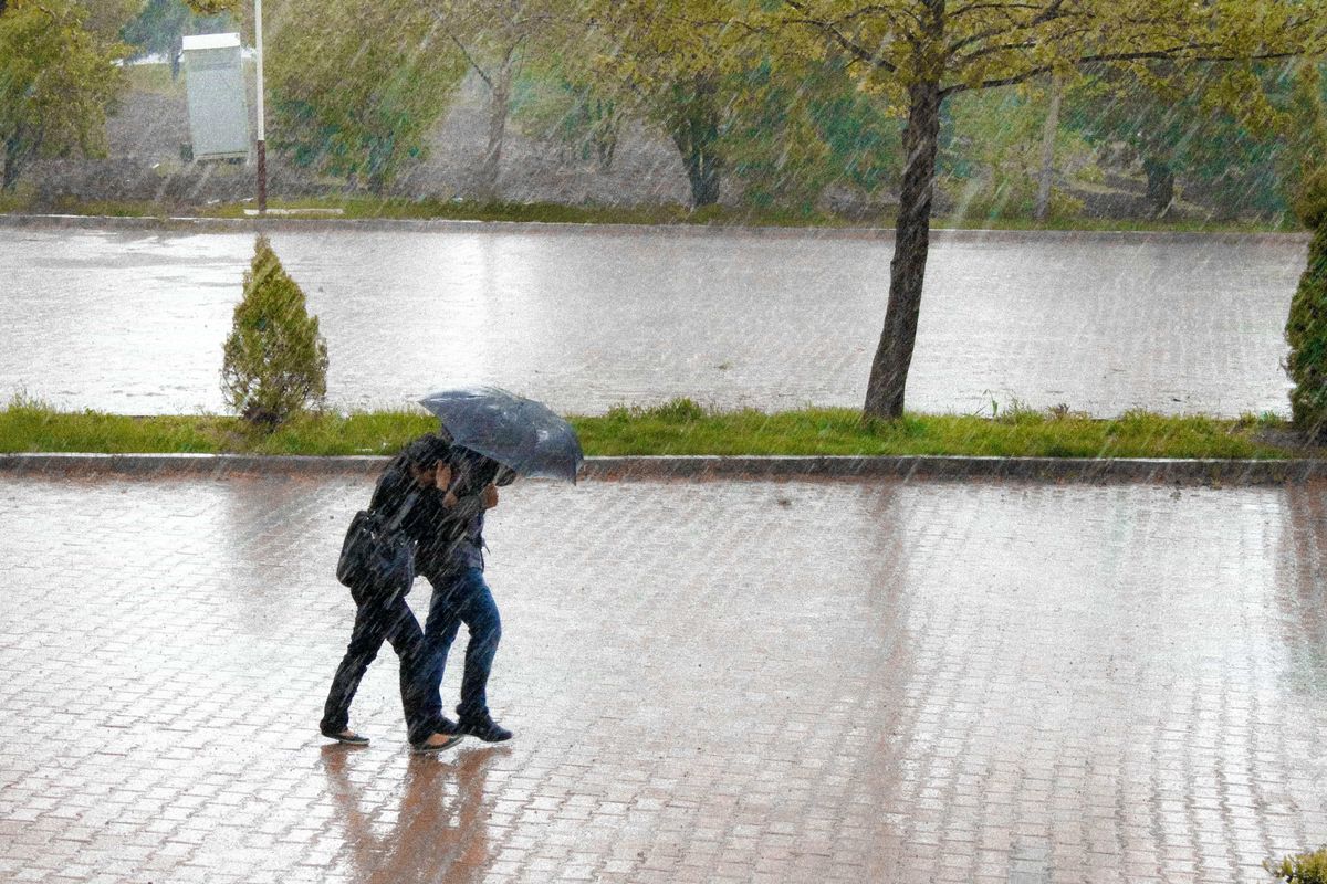 Día lluvioso en una calle. Dos personas bajo la lluvia con un paraguas