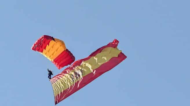 Un paracaidista del Ejército desciende sobre el Paseo de la Castellana en Madrid con la bandera de España. Un paracaidista del Ejército desciende sobre el Paseo de la Castellana en Madrid con la bandera de España.