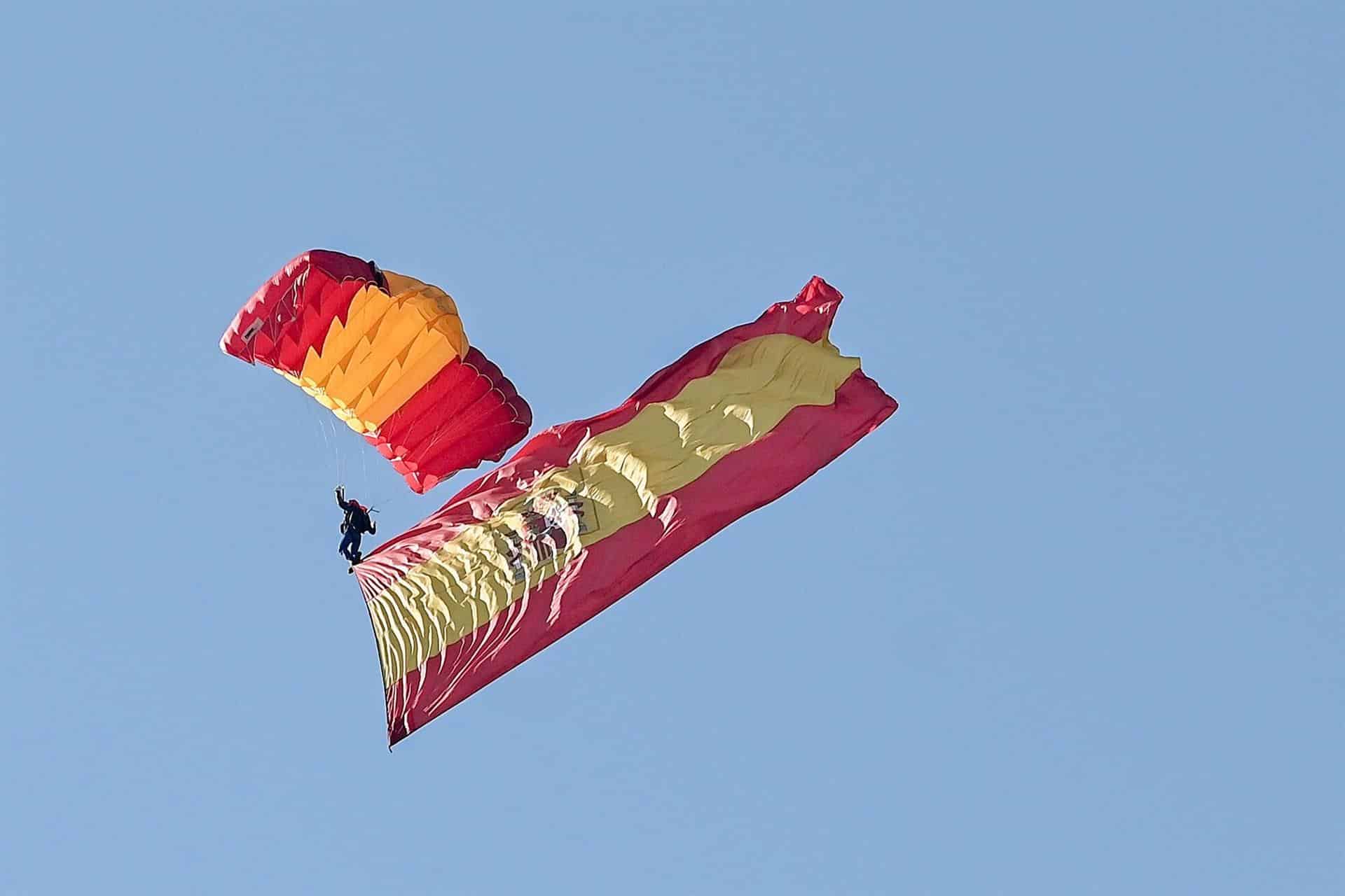 Un paracaidista del Ejército desciende sobre el Paseo de la Castellana en Madrid con la bandera de España.