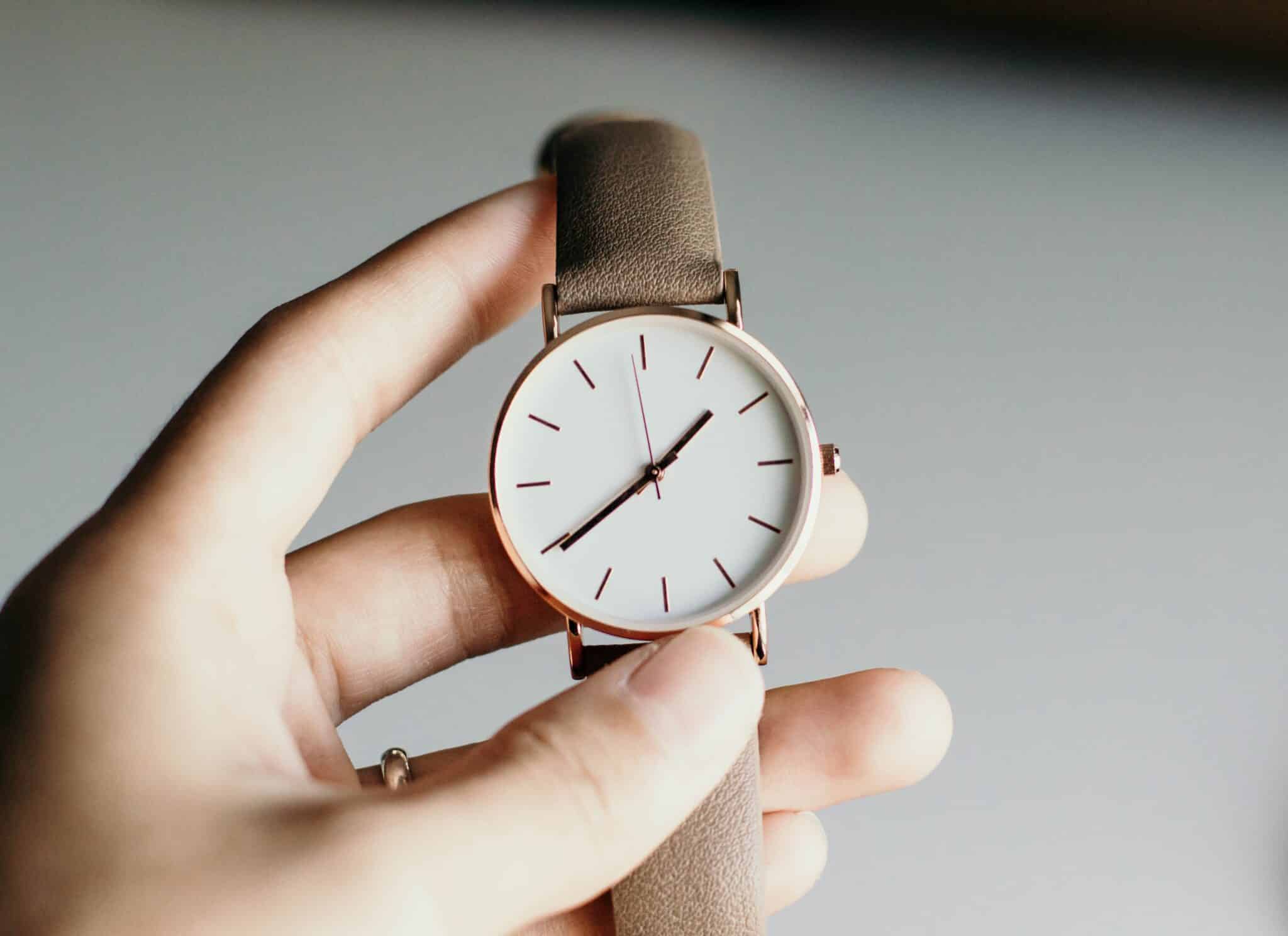 Mano sosteniendo un reloj de muñeca en relación al cambio de hora de invierno