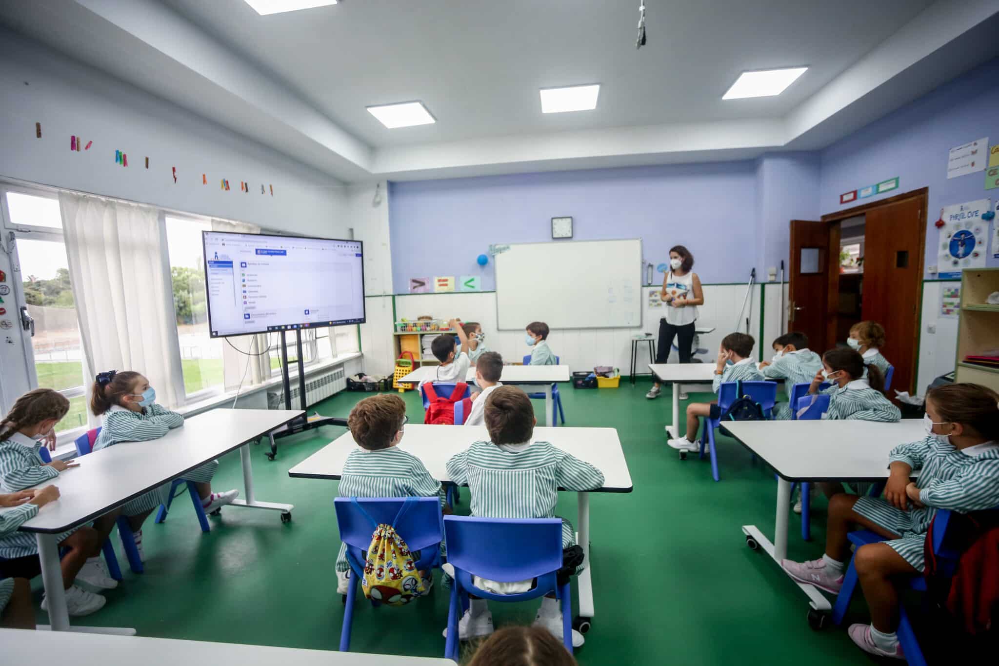 Varios niños escuchan las explicaciones de su profesora en una clase del colegio Virgen de Europa durante el primer día de clase del curso 2021-22, a 6 de septiembre de 2021, en Boadilla del Monte, Madrid (España). El tercer curso escolar en un contexto de pandemia arranca esta semana en toda España, con el 39,4% de los jóvenes mayores de 12 años vacunados con pauta completa contra la COVID y prácticamente el 100% de los profesores, así como las mismas medidas sanitarias para evitar contagios del curso anterior.