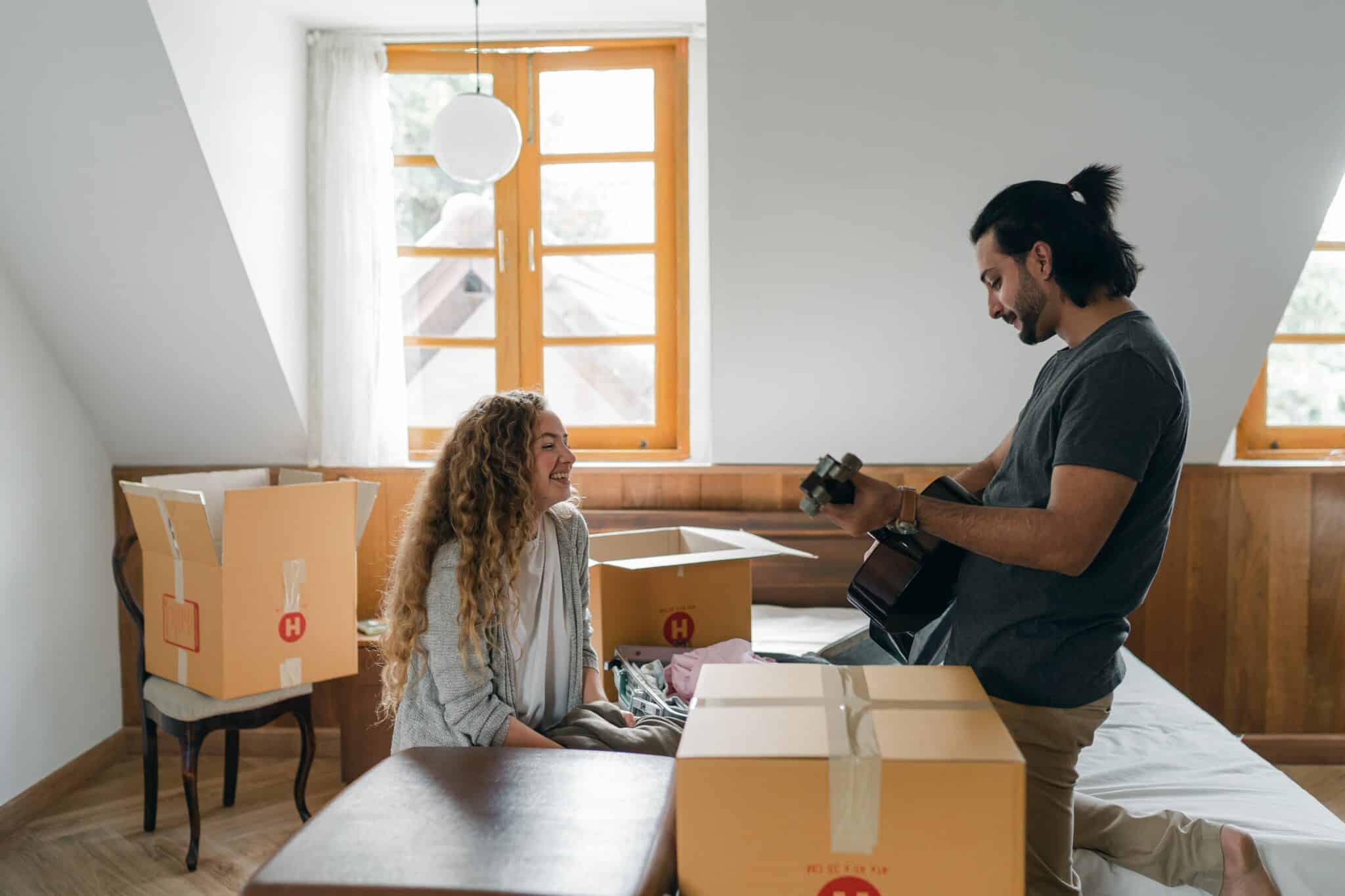 Dos jóvenes deshacen cajas de mudanza.