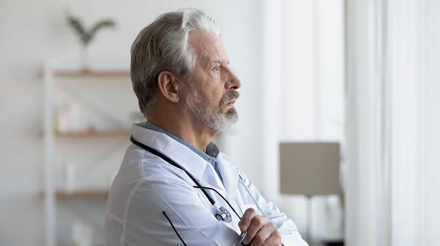 Imagen de un médico mirando a la ventana con cara de preocupación