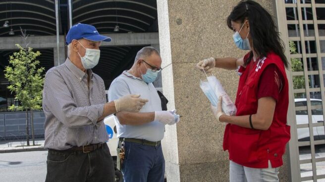 Miembro de la Cruz Roja entregando mascarillas