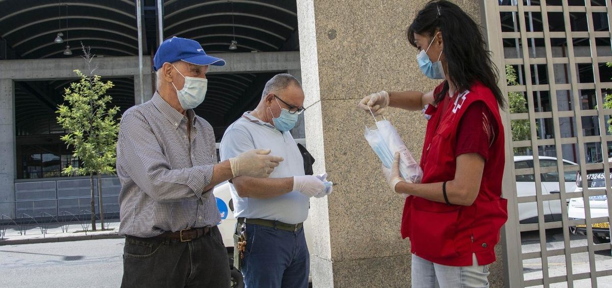 Miembro de la Cruz Roja entregando mascarillas