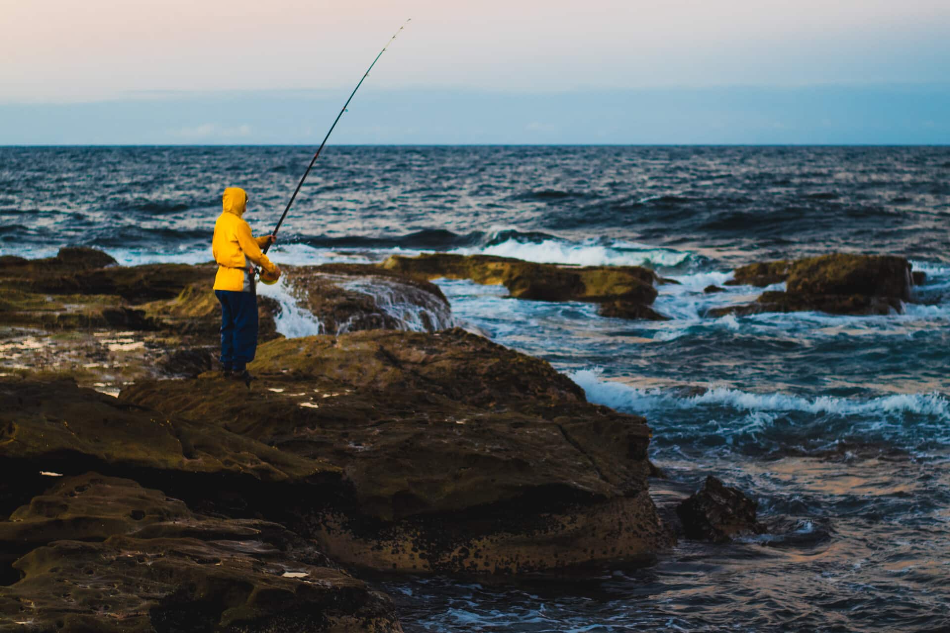 Pescador en una zona rocosa junto al mar