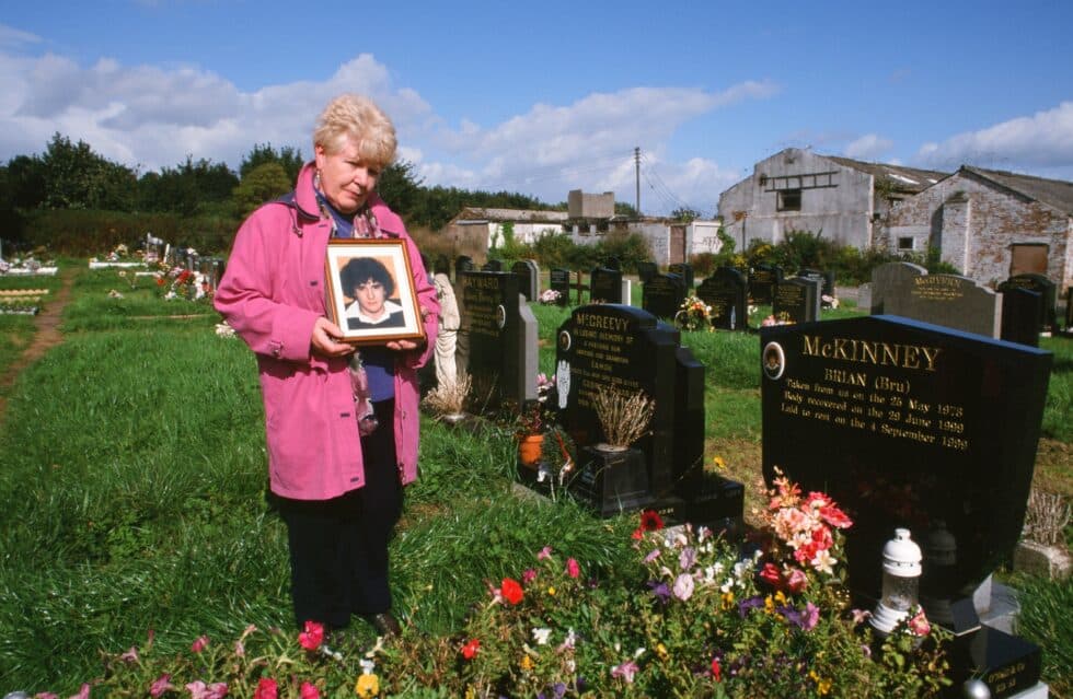 Margaret McKinney muestra la fotografía de su hijo Brian ante su tumba. El IRA asesinó al muchacho en 1978, hizo desaparecer su cadáver y negó su implicación en el crimen hasta que en 1999 facilitó información del paradero de sus restos bajo presión del gobierno estadounidense. La mujer le cuenta a Rogelio Alonso sus sentimientos más íntimos: “Morí con Brian y mi obsesión fue encontrarle. No he podido dejar de imaginarme el momento en que lo asesinaron. Veo su cara y sus manos atadas y sé que estaría pensando en mí. En 1999 me visitó el político Gerry Adams (algunos documentos oficiales británicos e irlandeses, desclasificados por haber transcurrido treinta años, le señalan como una importante figura del IRA Provisional a principios de la década de los setenta) y se comprometió a recuperar sus restos. Jamás me pidió perdón. Ni siquiera en privado, cuando estábamos a solas él y yo. Durante años negó que el IRA lo hubiera asesinado. Cuando finalmente lo admitió dijo que son cosas que pasan en una guerra y que todo el mundo sabe la opinión que en Irlanda se tiene de los confidentes. Él sabía muy bien que mi hijo no era un confidente, ni jamás tuvo nada que ver con el grupo armado. Si lo hubiese sido, habrían dejado su cadáver abandonado en cualquier cuneta, como hacían para disuadir a otros”. Belfast (Irlanda del Norte), setiembre de 2001