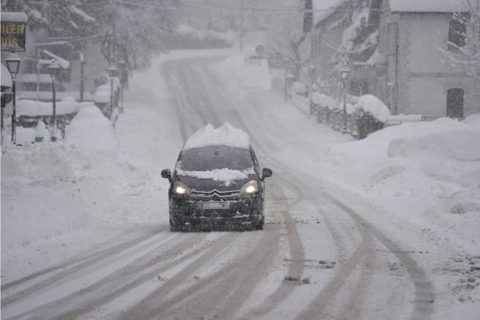 Un coche circula por la carretera nevada del Pirineo Aragonés, en Huesca