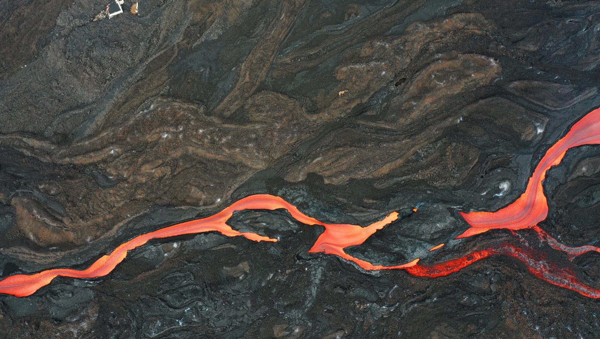 El tejado de una vivienda sobresale de la lava ya solidificada junto a una rio de magma que discurre por la fajana creada por la erupción del volcán Cumbre Vieja. La sismicidad asociada al volcán ha aumentado en las últimas horas en los niveles profundos a más de 20 kilómetros bajo tierra