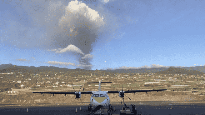 Un avión de Binter en la pista del aeropuerto de La Palma, con el volcán en erupción al fondo