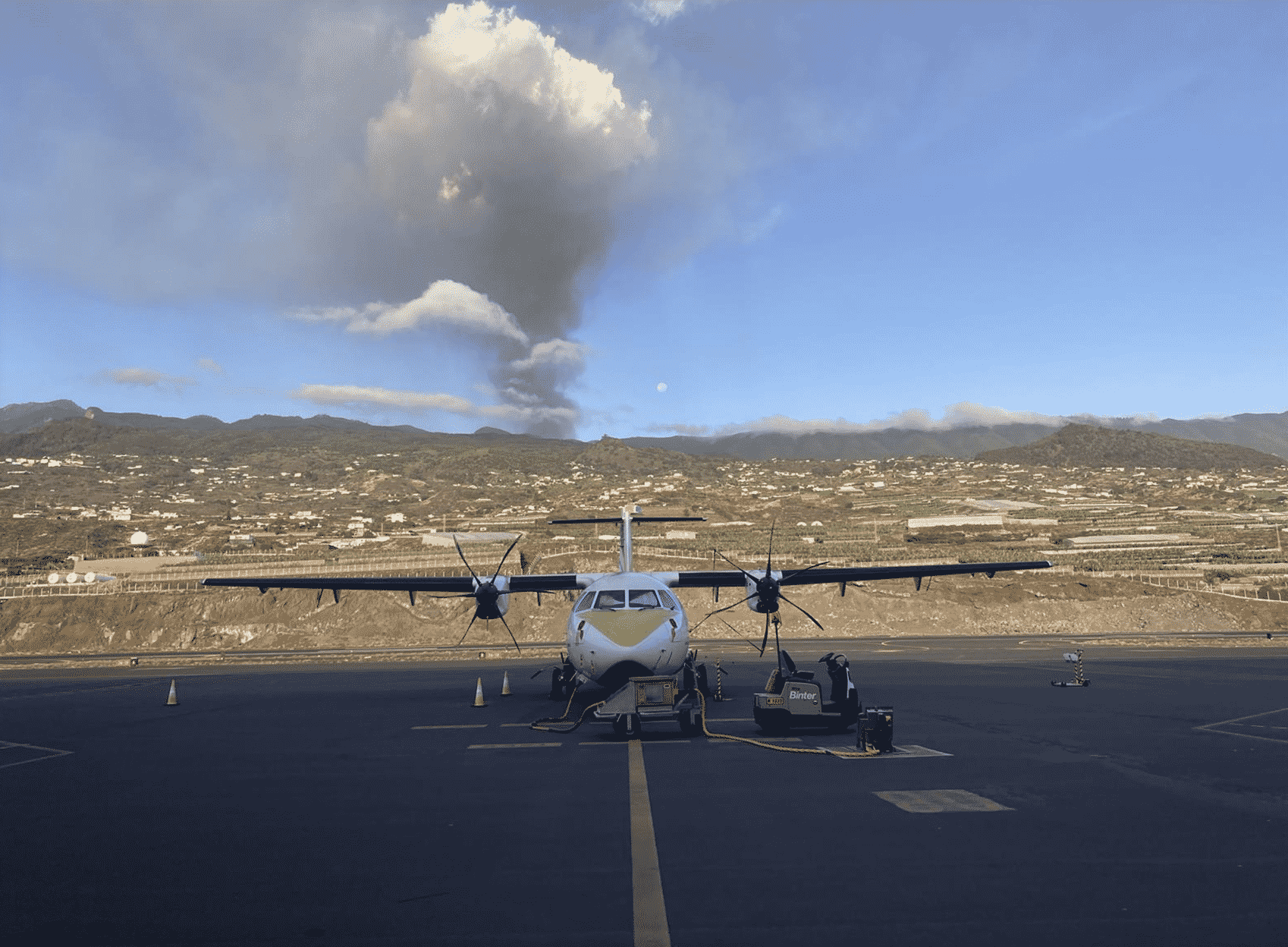 Un avión de Binter en la pista del aeropuerto de La Palma, con el volcán en erupción al fondo