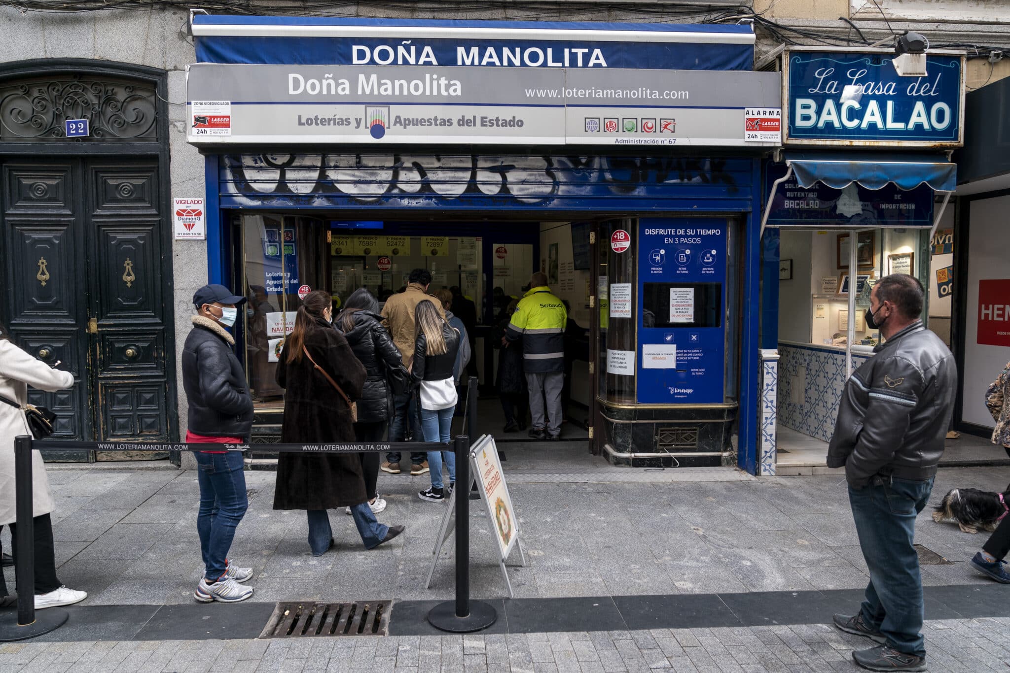 Un grupo de personas esperan a las puertas de la administración de lotería Doña Manolita, a 2 de noviembre de 2021, en Madrid