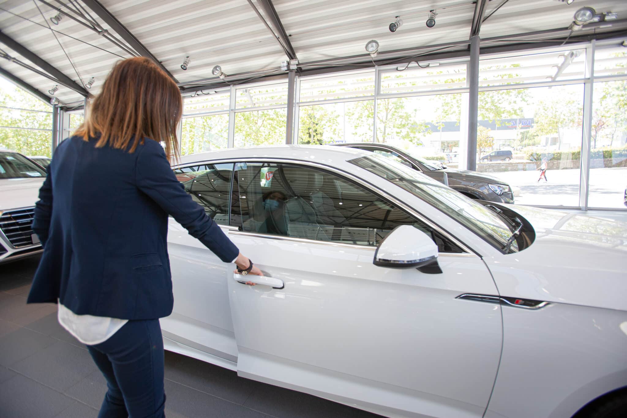Una mujer abre un coche aparcado en el interior de un concesionario en VItoria-Gasteiz, Álava.