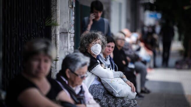 Personas que hacen fila afuera de un banco donde pagan jubilaciones y planes sociales este viernes, en Buenos Aires, Argentina.