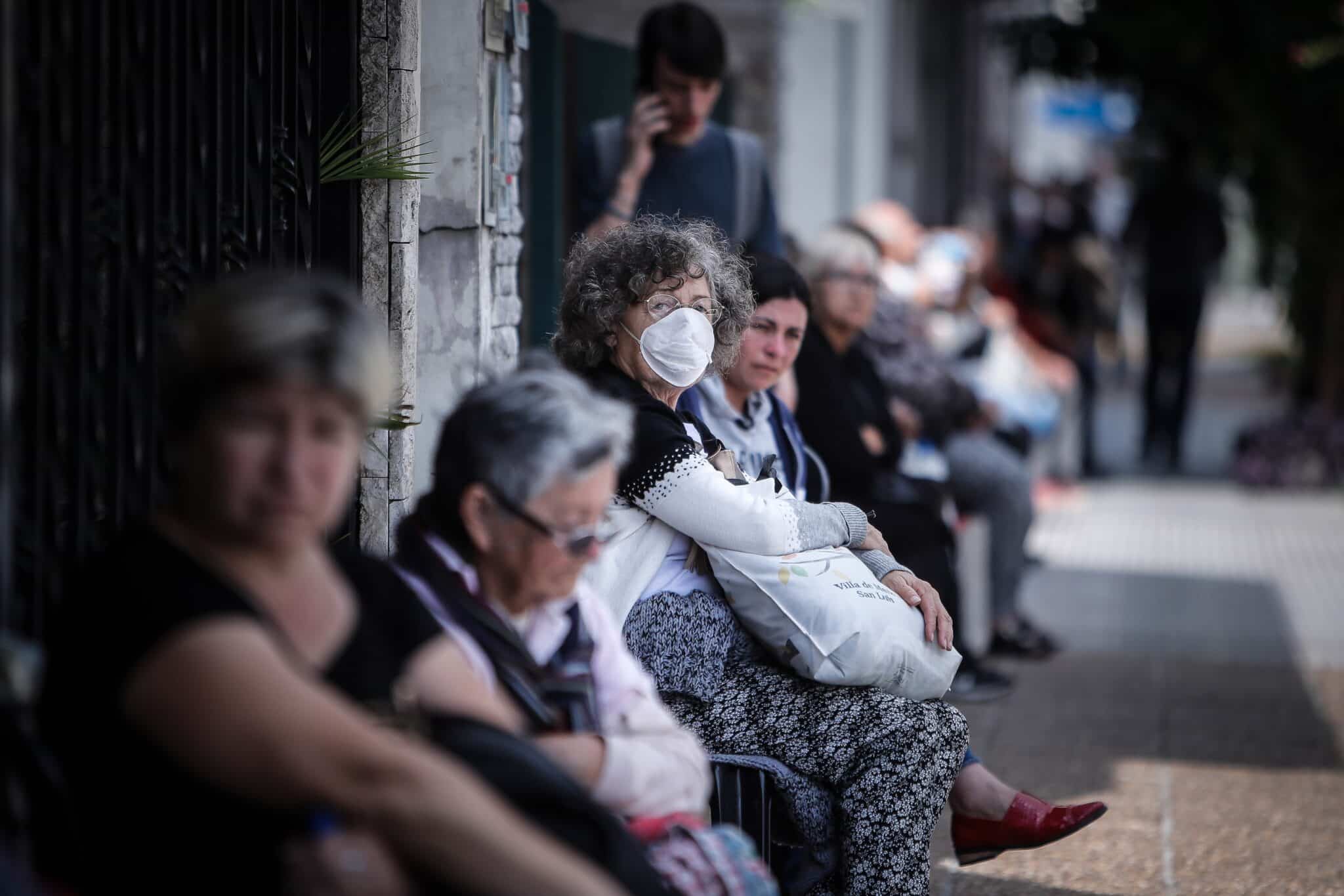 Personas que hacen fila afuera de un banco donde pagan jubilaciones y planes sociales este viernes, en Buenos Aires, Argentina.