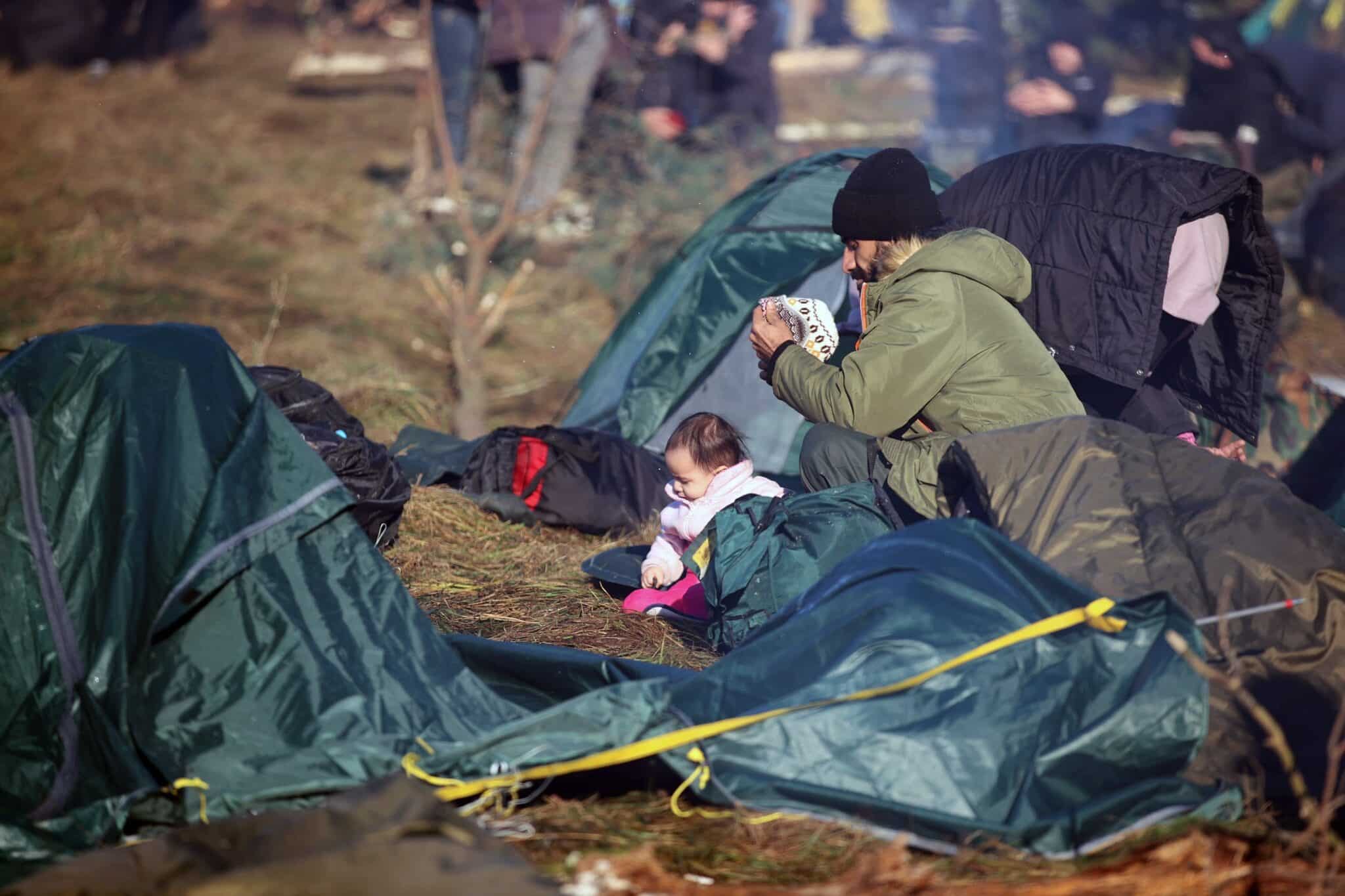 Un hombre y su bebé acampados en la frontera entre Bielorrusia y Polonia