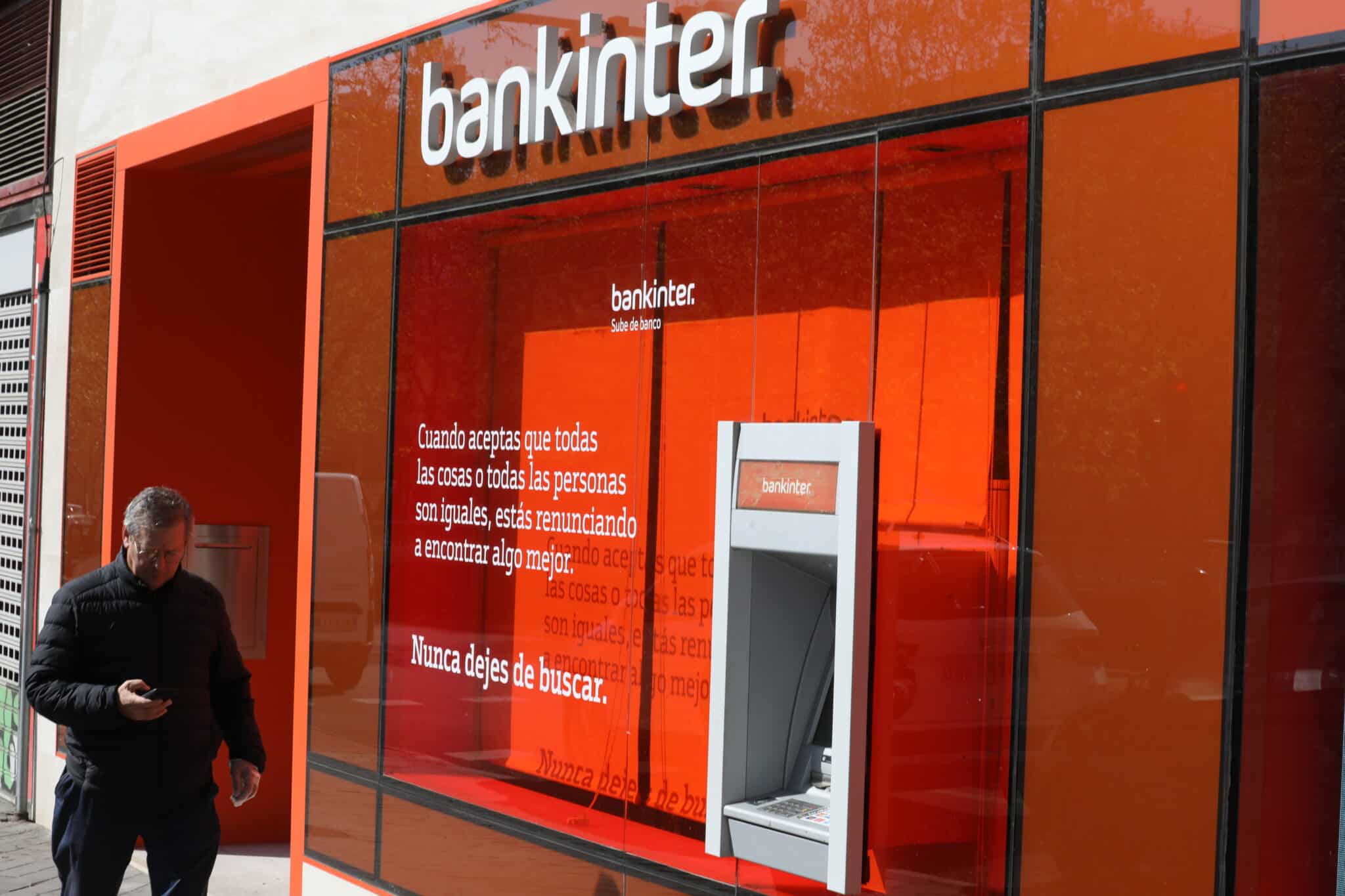 Un hombre pasa al lado de un cajero del banco Bankinter en una de sus oficinas