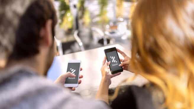 Bizum dejará de estar operativo el 12 de noviembre Dos personas utilizan Bizum en sus teléfonos móviles.