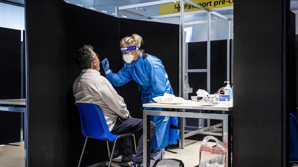 Una sanitaria realiza un test en el aeropuerto de Schipol, en Ámsterdam, a un pasajero procedente de Sudáfrica