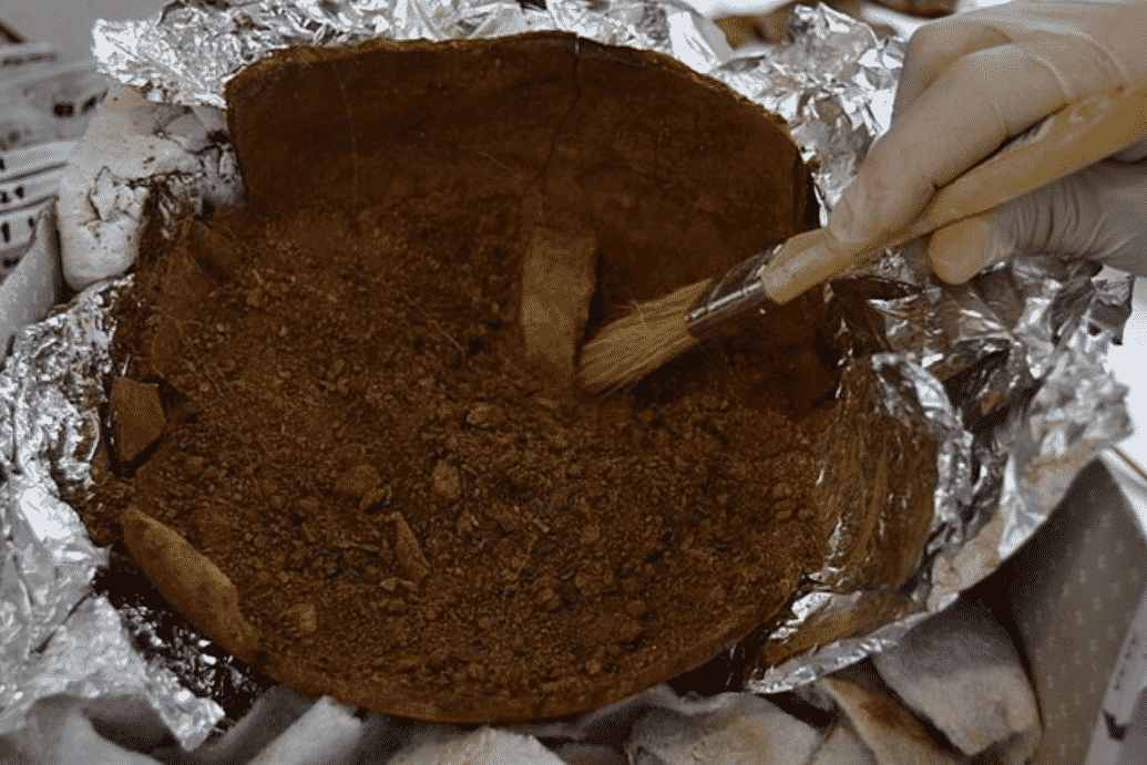 Trabajos de recuperación de los restos óseos dentro de la olla de cerámica encontrada en 'O Castrillón', en el municipio de Larouco